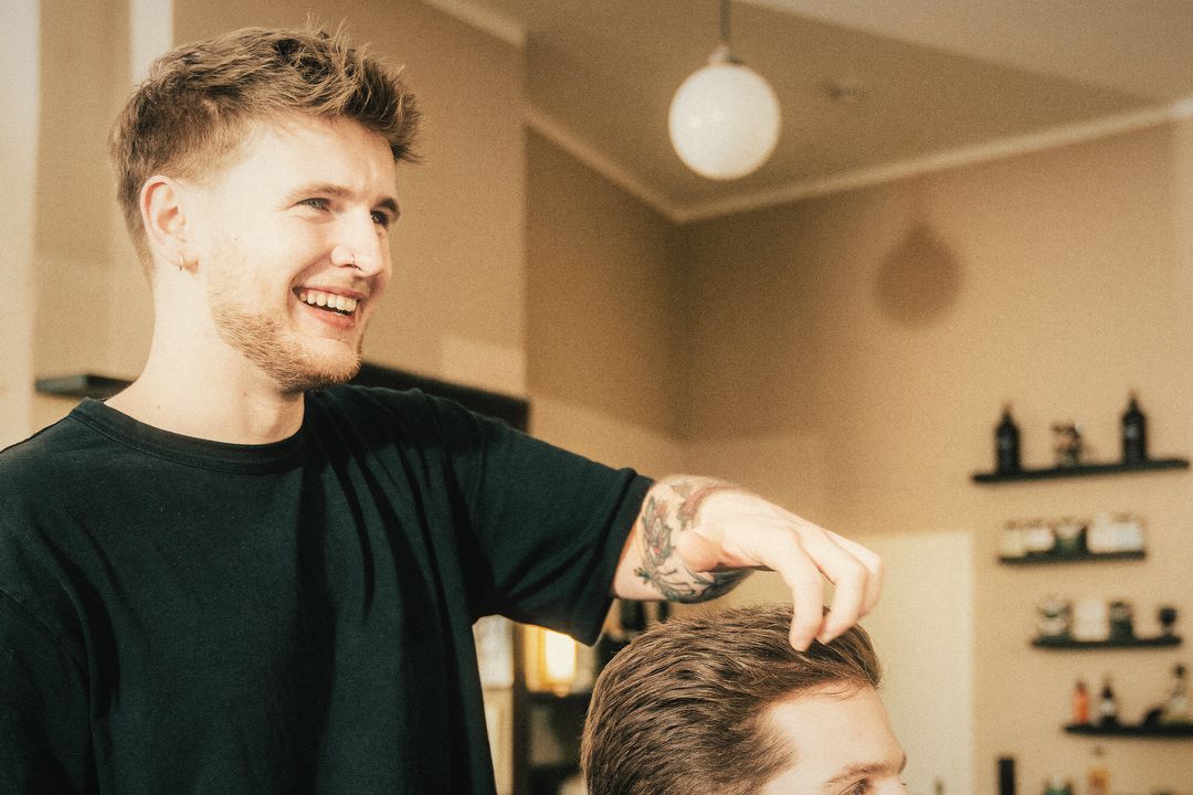 Herrengut-Barbier lacht, während er einem Kunden die Haare stylt
